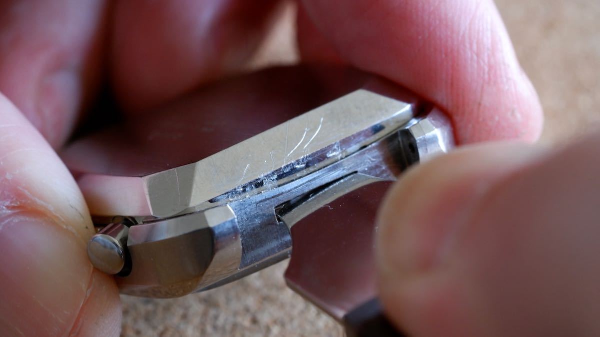 Using a case opener to push the tab in the side of a two-piece watch.