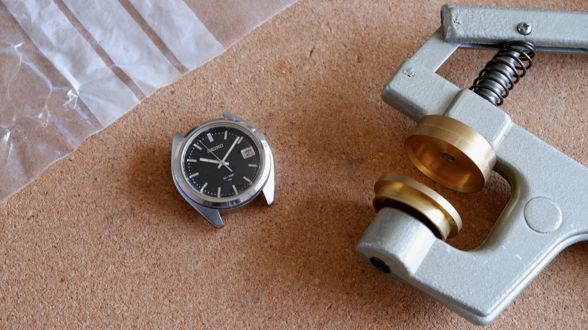 A crystal press next to a Seiko watch.