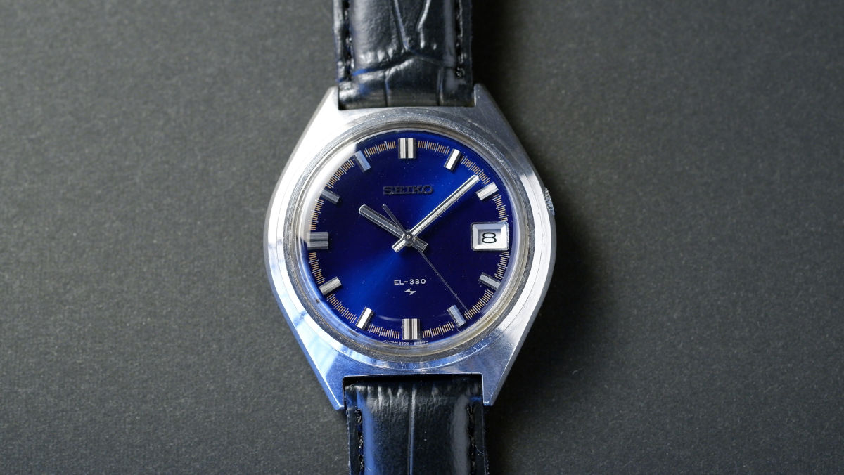 The same watch with strap back on and a clear crystal and deep blue dial.