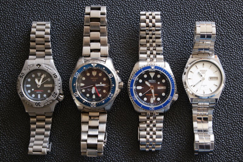 Two Seiko watches with titanium bracelets and two with stainless steel bracelets.